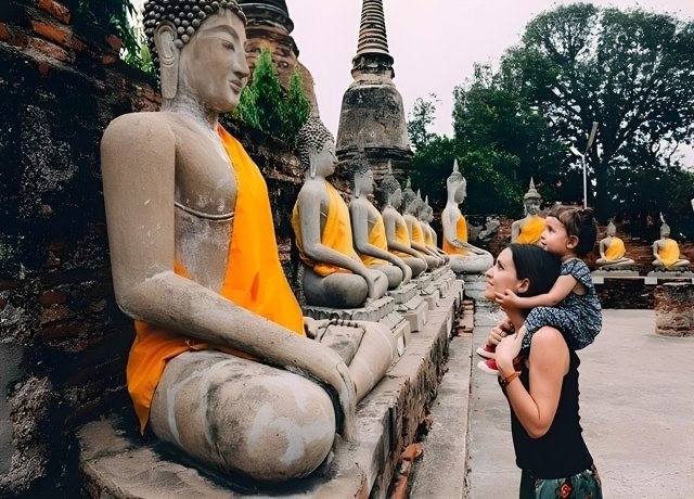 Mother and child view a traditional statue.